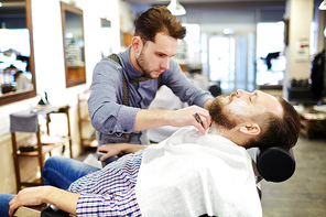 Young man having his beard shaven at barbershop