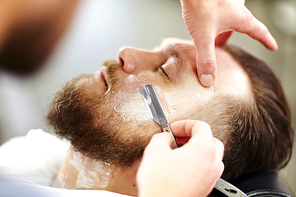 Barber shaving bearded man