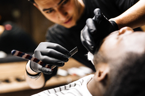 Barber shaving client with razor blade