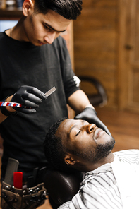 Barber shaving beard of young African man