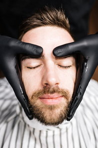 Young man having his face massaged in parlor