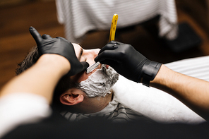 Barber trimming beard of his client