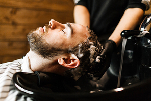 Hairdresser foaming shampoo in client hair while washing it