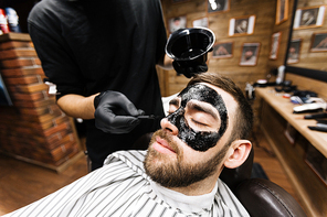 Handsome young man having purifying mask on his face