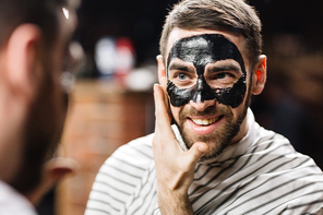 Happy young man with peel-off mask on his face