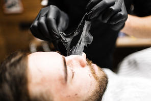 Relaxed man having peel-off mask on face