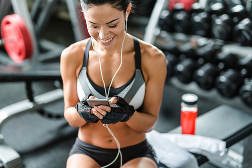 Fit young woman listening to music in gym