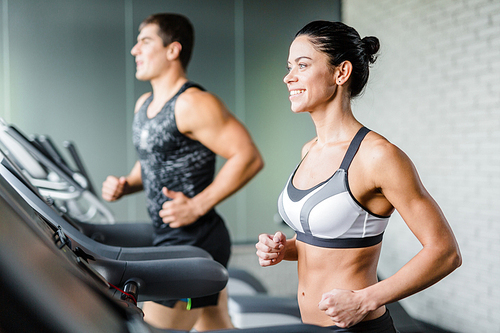 Happy woman runing on treadmill on background of man