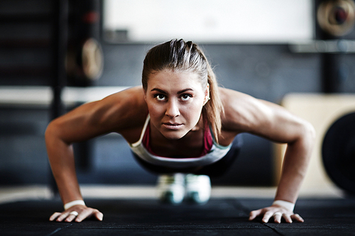 Active woman doing push-ups in gym