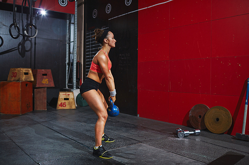 Strong young woman exercising with kettle