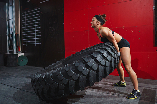 Strong woman flipping tyre during workout