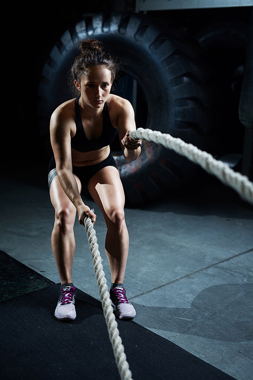 Fit woman training with ropes in gym