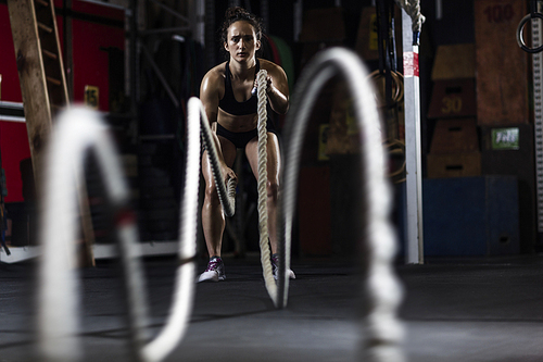 Active young woman in activewear working out with ropes