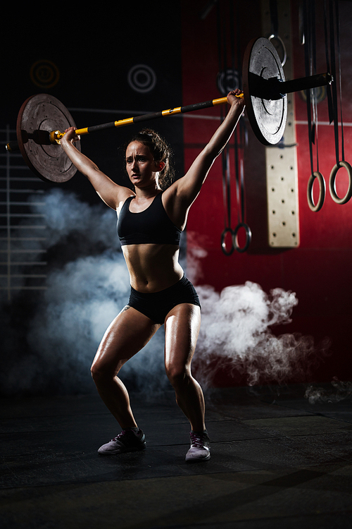 Sportswoman lifting heavy weight during cross training