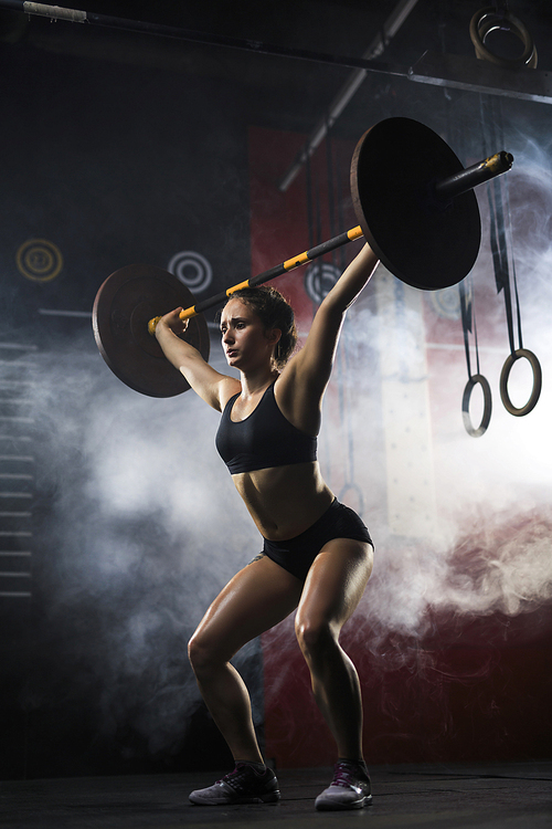 Woman lifting heavy weight in sports club