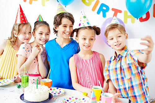 Row of happy kids making selfie at birthday party