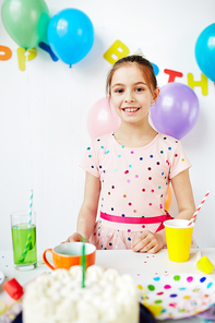 Adorable girl standing by birthday table