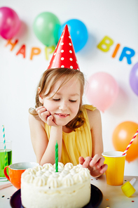 Adorable girl tasting birthday cake with whipped cream