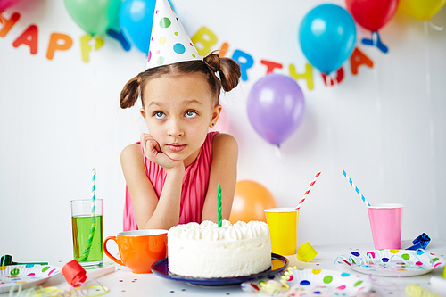 Cute girl making wish by birthday cake