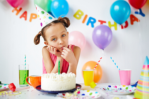 Little girl sitting at the table and eating cake