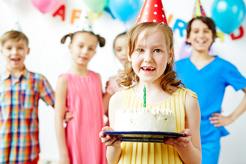 Little girl holding birthday cake and smiling