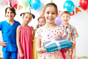 Happy girl standing with present with her friends behind