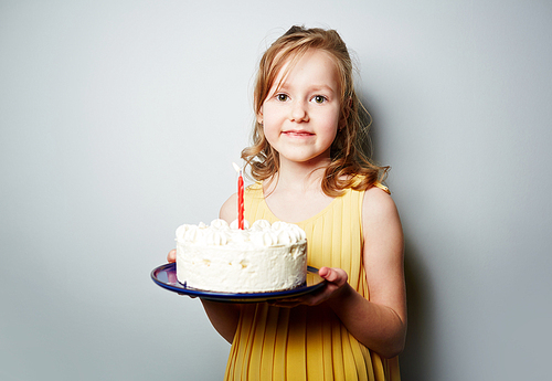 Pretty youngster holding birthday cake with whipped cream