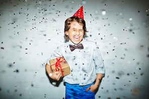 Cheerful boy in birthday cap holding box with gift