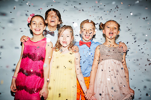 Group of happy children standing under falling confetti