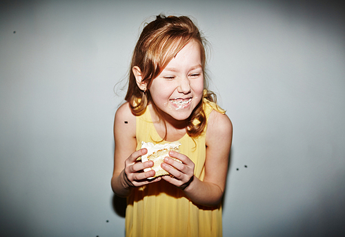 Cute girl eating tasty cake and laughing