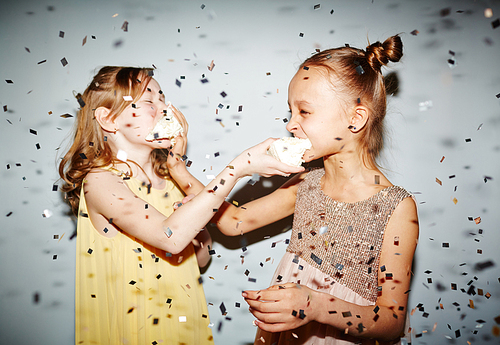 Two girls having fun with birthday cake under confetti rain