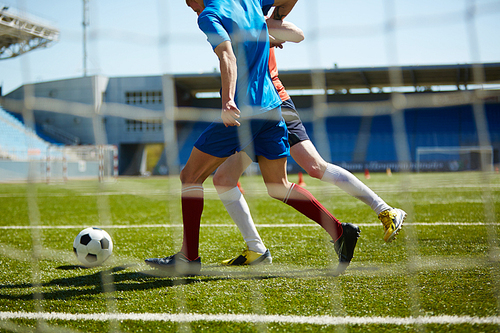 Sportsmen playing football on green field