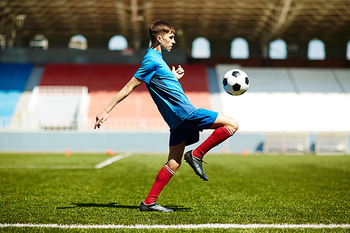 Young football player training alone in the stadium