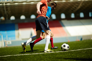 Two opposing footballers following soccer ball