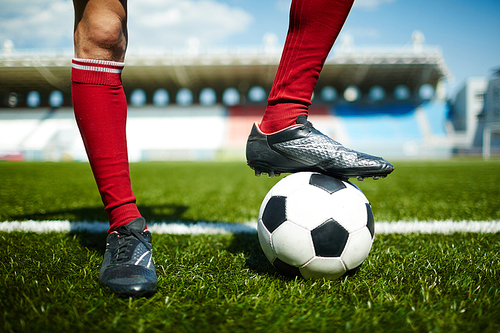 Close-up of male leg in sports boot on soccer ball