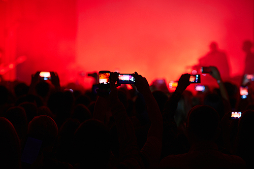 People taking photographs with touch smart phone during a music concert