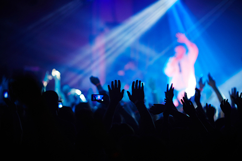 Ecstatic fans with raised hands enjoying concert of their favorite musician