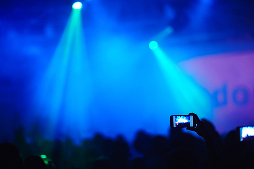 Female hands recording video with smartphone during a concert
