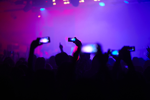 Hands of young people with smartphones recording pop concert