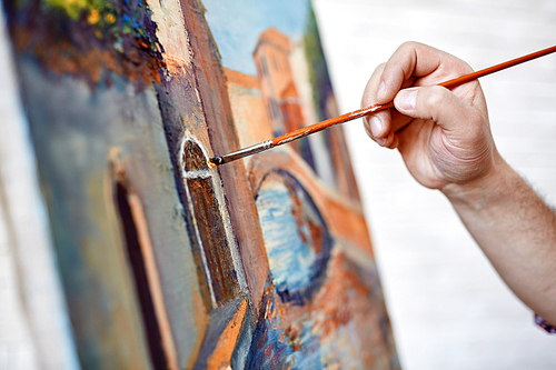 Close-up of male artist painting his picture with paintbrush