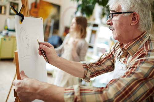 Mature man drawing on easel