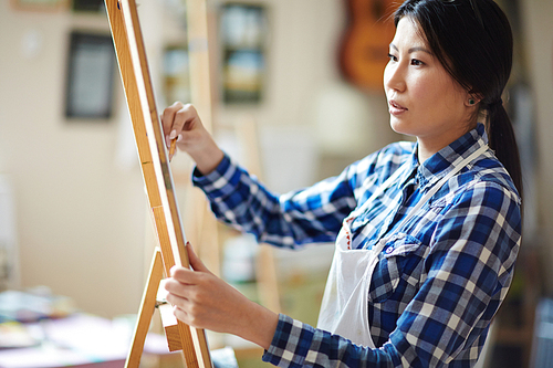 Serious female artist drawing on canvas