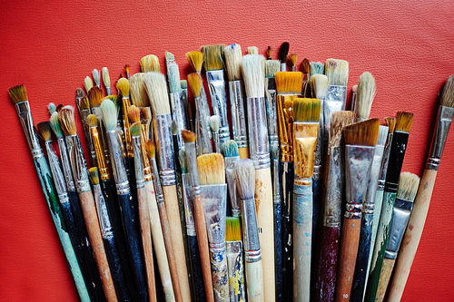 Paint-brushes on red leather background