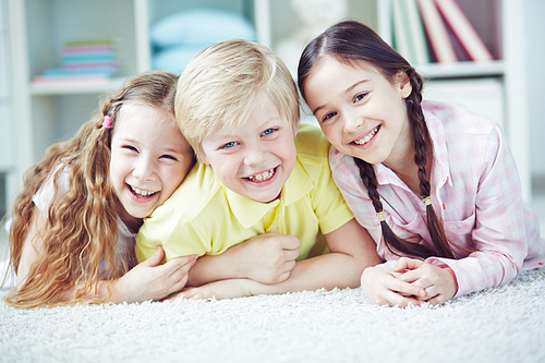 Portrait of three happy friends lying together on the floor