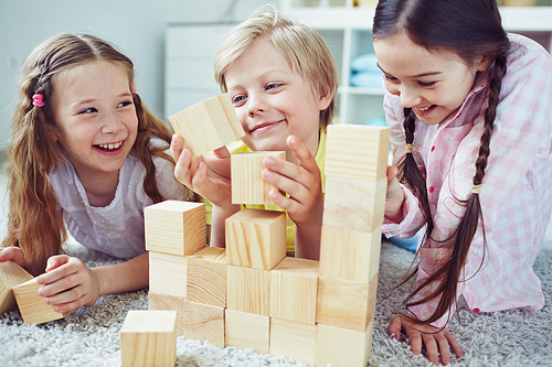 Cute children playing with wooden blocks in kindergarten