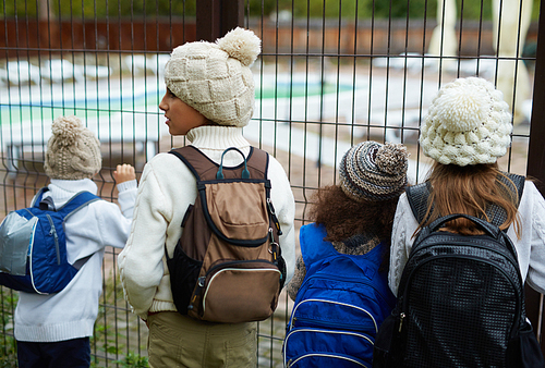 Youngsters in knitted caps standing by bars