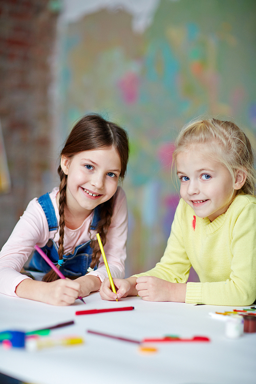 Smiling schoolgirls drawing with crayons