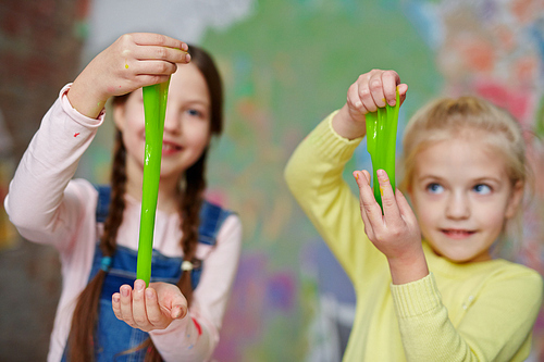 Little girls pulling slime between palms