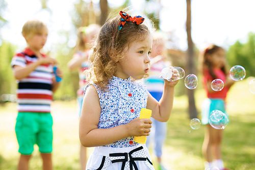 Little kid blowing soap bubbles outdoors