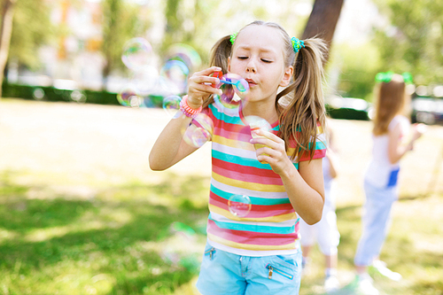 Youthful girl with soap bubbles having fun outdoors